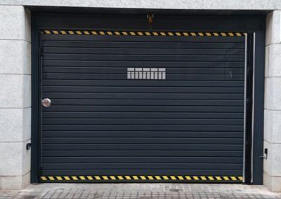 Puerta batiente metálica una hoja gris. Acceso parking. Construcción puertas metálicas en el Vallès