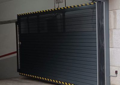 Puerta metálica batiente gris una hoja abierta. Acceso parking. Construcción en tallermetalico.com