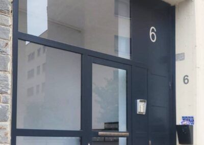 Puerta metálica de entrada portal de vecinos. Perfil plano de hierro acristalado